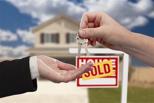 تحویل کلیدهای خانه جلوی تابلوی املاک و مستغلات و خانه فروخته شده جدید
