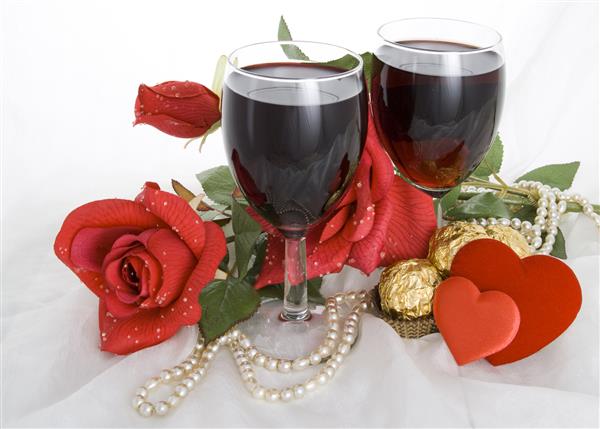 گل سرخ آب نبات دو لیوان شراب دو قلب و یک نخ مروارید روی زمینه سفید