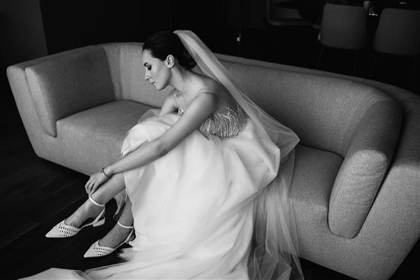 عروس کفش هایش را می پوشد و روی مبل نشسته است