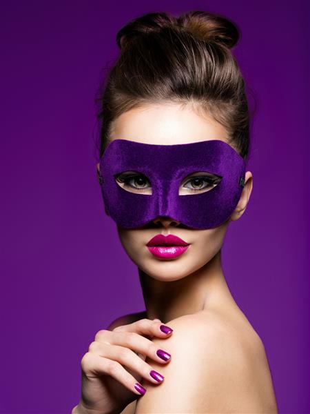 پرتره یک زن زیبا با ناخن بنفش و ماسک تئاتر روی صورت