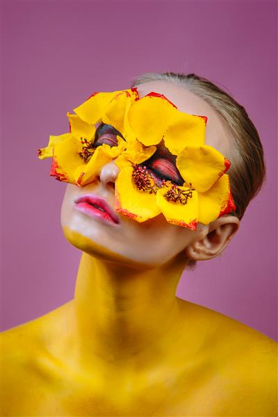 مدل زن با گلهای زرد در اطراف چشمانش بدن زن به رنگ زرد رنگ شده است