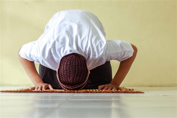 مرد مسلمان با ژست سجده بر روی تشک نماز می خواند