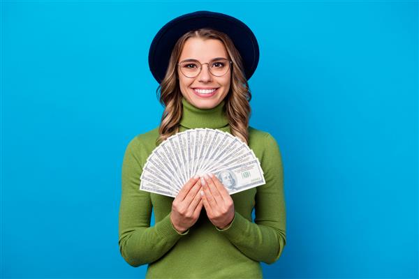 دختری با کلاه و عینک طرفدار پول را در دست دارد