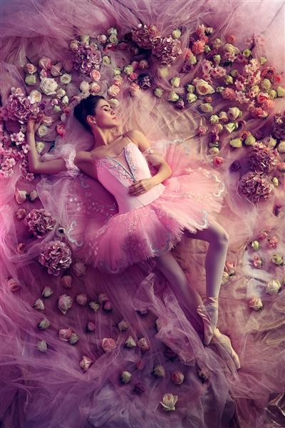 رویاهای شیرین نمای بالای زن جوان زیبا با توتو باله صورتی با گل احاطه شده است خلق و خوی بهاری و لطافت در نور مرجانی