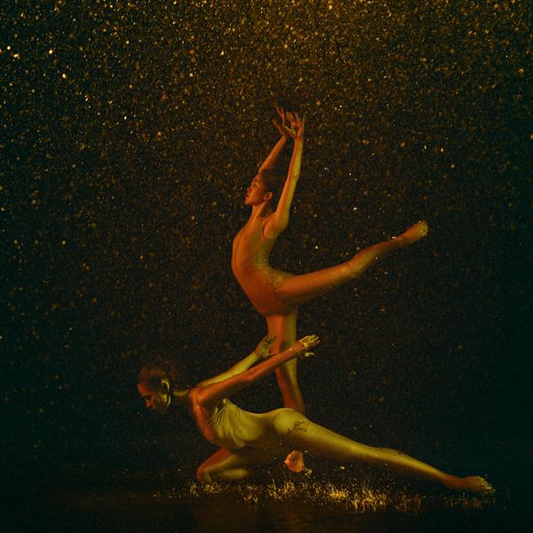 شگفت انگیز دو رقاص زن جوان باله زیر قطره آب و اسپری مدل های قفقازی و آسیایی با هم در چراغ های نئون می رقصند باله و مفهوم رقص معاصر عکس هنری خلاقانه