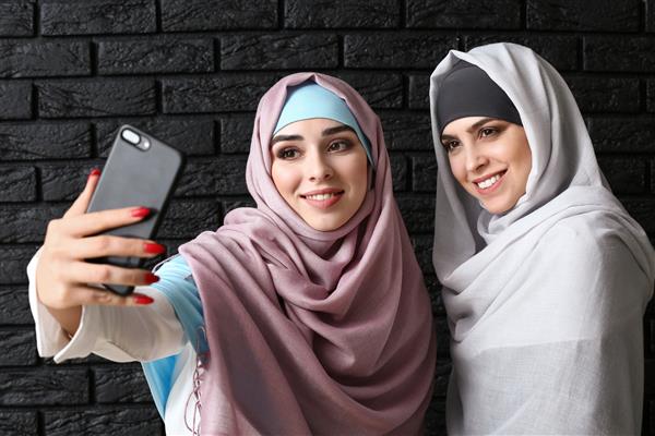 زنان مسلمان زیبا در حال گرفتن سلفی در پس زمینه تیره