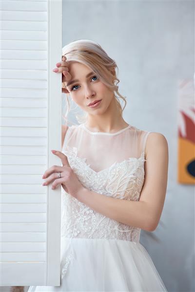 دختر بلوند با لباس عروس سفید زیبا یک عروس زن قبل از عروسی منتظر داماد است