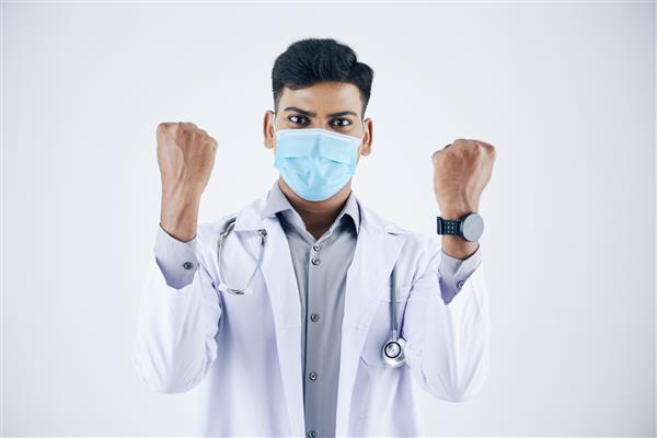 پزشک هیجان زده جوان هندی با ماسک محافظ در حال حرکت پمپ جدا شده روی سفید