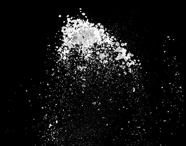 انفجار پودر سفید جدا شده در زمینه سیاه برای منابع گرافیکی