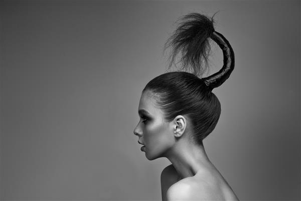 دختری جوان با آرایش روشن و پوستی درخشان مدل موی خلاقانه روی سر روی خاکستری