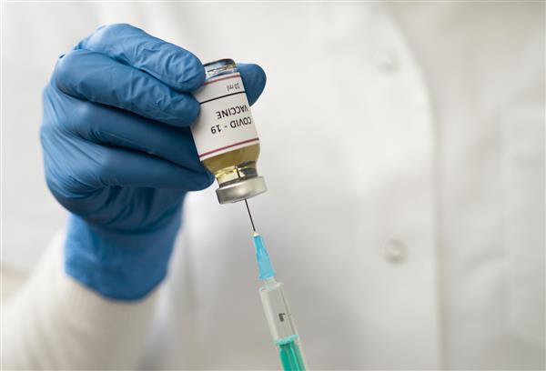 نمای جلوی پزشک که از واکسن کرونا استفاده می کند