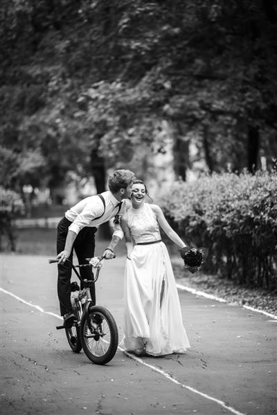 پریدن عروس با دوچرخه عروس به لباس برگشت لبخند عکس سیاه و سفید در پارک رمانتیک اروپایی