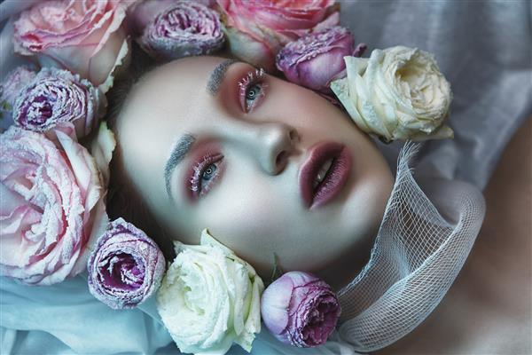 مدل با آرایش خلاقانه و گل هایی در اطراف صورت خود ژست گرفته است