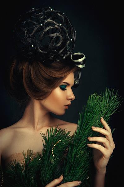 زن جوان موهای تیره با شاخه صنوبر ژست می گیرد