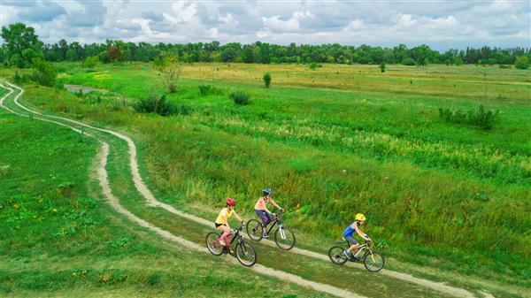 دوچرخه سواری خانوادگی با دوچرخه در فضای باز از نمای هوایی از بالا مادر فعال شاد با فرزندان از تفریح ​​ ورزش خانوادگی و تناسب اندام لذت ببرید