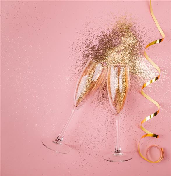 دو لیوان شامپاین برشته شده با کوفتی طلایی زرق و برق و سرپانتین در زمینه صورتی تخت دراز کشید مفهوم شب جشن