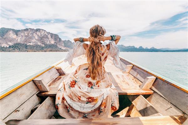 مدل جوان شیک پوش با لباس بوهو روی قایق کنار دریاچه