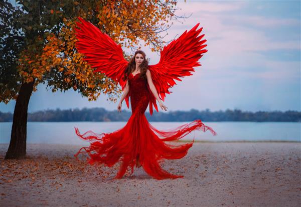زن فانتزی زیبای جوان فرشته افتاده در هوا در نزدیکی درختی با برگ های نارنجی
