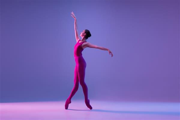 رقصنده باله جوان و برازنده ایزوله شده روی پس زمینه استودیو بنفش در نور نئون