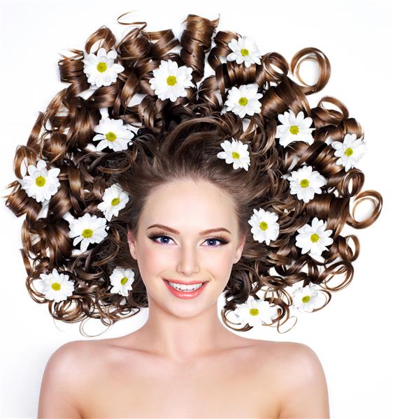 زن جوان خندان با گل هایی با موهای بلند روی سفید