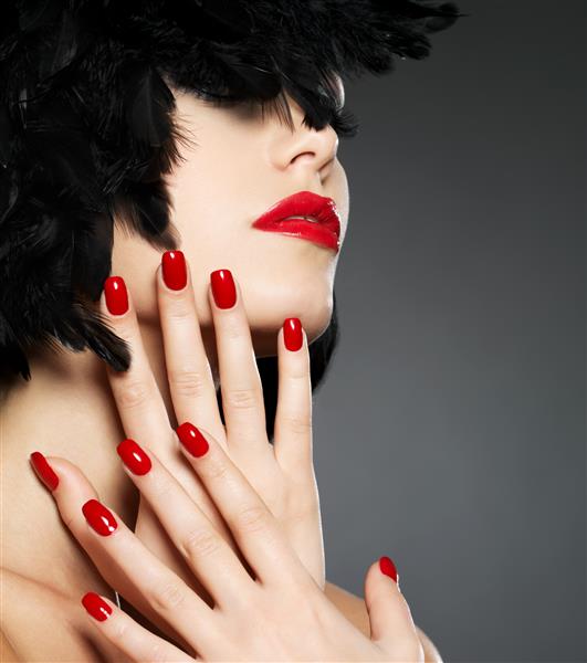 عکس ماکرو زن با ناخن های قرمز مد و لب های حسی