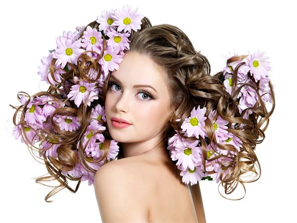 گل های بهاری در موهای مجعد و زیبای زن جوان زیبا - فضای سفید