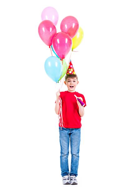 پسر خندان شاد با تی شرت قرمز که بادکنک های رنگارنگ در دست دارد - جدا شده روی یک سفید