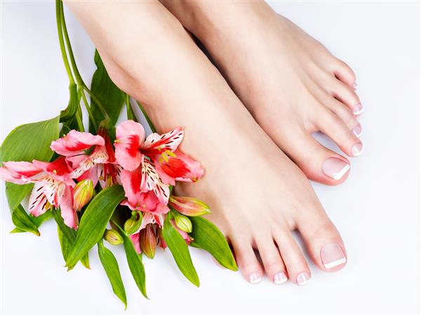 عکس نزدیک از پاهای زن با پدیکور فرانسوی سفید روی ناخن
