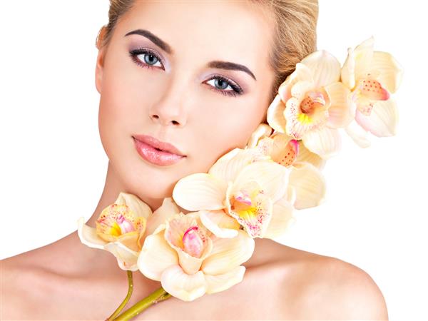 زن زیبای جوان و زیبا با پوست سالم و گلهای نزدیک به صورت - جدا شده روی سفید