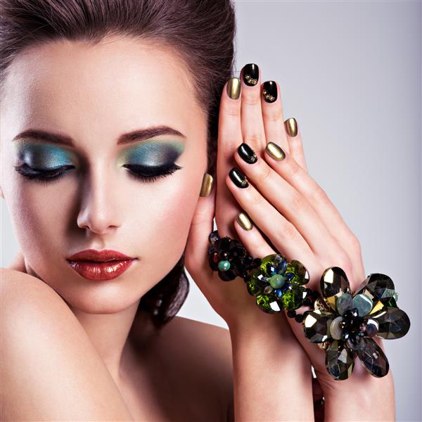 چهره زیبای زن با آرایش سبز و جواهرات شیشه ای ناخن های خلاقانه