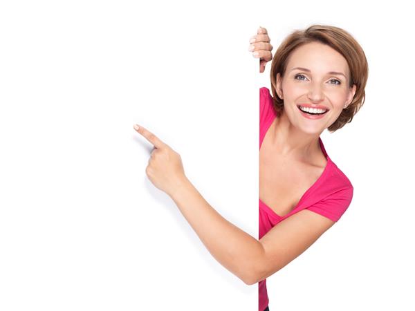 زن شادی که با انگشت خود روی بنر جدا شده روی دیوار سفید اشاره می کند