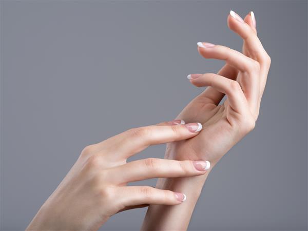 دست های زیبای زن با مانیکور فرانسوی روی ناخن