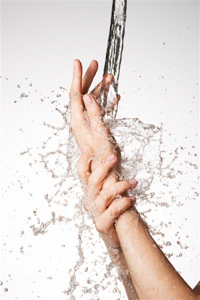 دست های زن نزدیک زیر جریان آب پاشیده - مفهوم مراقبت از پوست