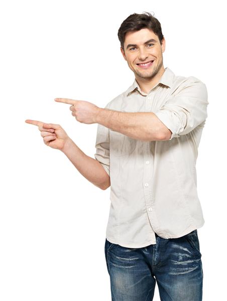 مرد جوان خندان با انگشتانش در سمت راست که روی دیوار سفید جدا شده است اشاره می کند