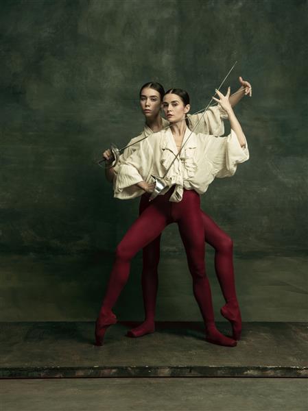 پرشور دو رقصنده زن جوان مانند دوئل با شمشیر روی دیوار سبز تیره رقص مدل های قفقازی با هم باله و مفهوم رقص معاصر