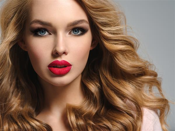 عکس یک زن جوان بلوند زیبا با لب های قرمز جذاب چهره جذاب دختر با موهای مجعد بلند نزدیک آرایش چشم دودی