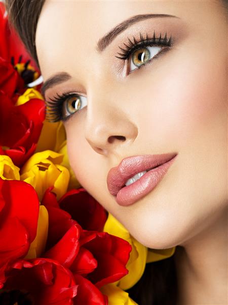 چهره زیبای نزدیک زن جوان با گل مدل جذاب با لاله های قرمز و زرد