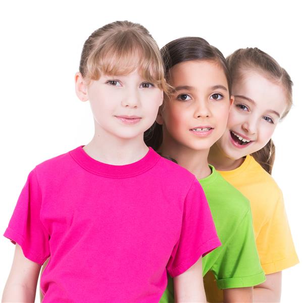 سه دختر خندان و ناز با تی شرت های رنگارنگ پشت یکدیگر روی دیوار سفید ایستاده اند