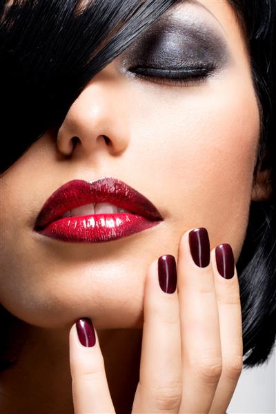 چهره زنی با ناخن های تیره زیبا و لب های قرمز جذاب مدل مد با موهای شات مشکی