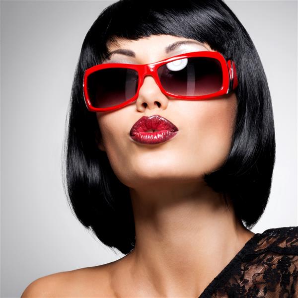 پرتره مد یک زن سبزه زیبا با مدل مو با عکس عینک آفتابی قرمز