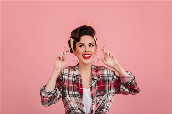 دختر اروپایی جوکند با پیراهن چهارخانه که روی پس زمینه صورتی ژست گرفته است زن زیبای پیناپ در حال ابراز احساسات مثبت