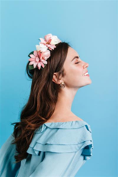 دختری زیبا که صمیمانه روی دیوار جدا شده لبخند می زند مدل در تاج گل ژست پرتره در پروفایل