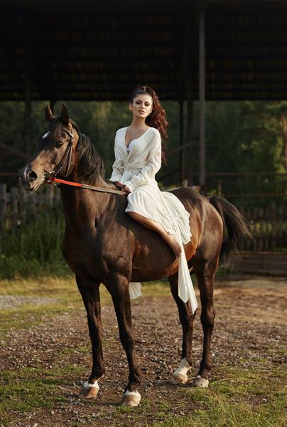 دختری با لباس بلند سوار بر اسب زنی زیبا سوار بر اسب در مزرعه ای در پاییز زندگی روستایی و مد اسب نجیب