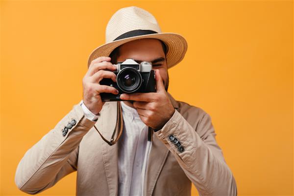 مردی با کلاه لبه پهن با دوربین یکپارچهسازی با سیستمعامل عکس می گیرد