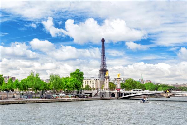 پل الکساندر سوم بر روی رودخانه سن و برج ایفل در خط افق پاریس فرانسه