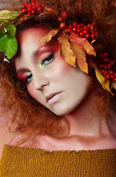 پرتره هنری از زنان پاییز در موهایش رنگ‌ها و آرایش‌های زنده پاییزی موهای مجعد قرمز و موهای حجیم برگ‌ها و توت‌های درخت روون روی سر و شانه‌های دختر
