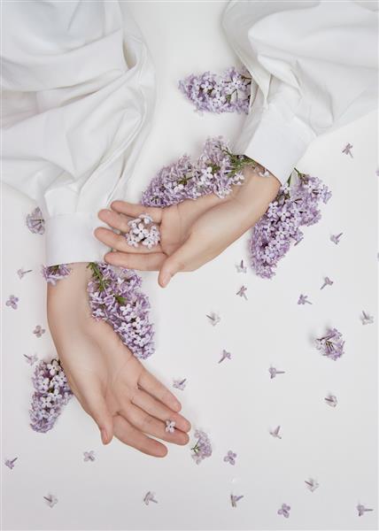 لوازم آرایشی طبیعی زنانه برای دست ساخته شده از گل و گلبرگ یاس بنفش پوست دست را مرطوب و نرم می کند گلهای یاس بنفش از آستین بازو بیرون زده است