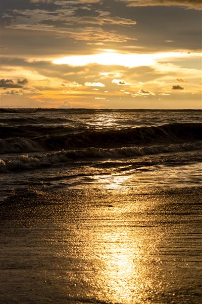 لحظه ساعت طلایی غروب خورشید در ساحل دریا با نور خورشید منعکس شده است