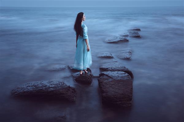 زن جوان زیبا در دریا در گرگ و میش قرار گرفتن در معرض طولانی مدت