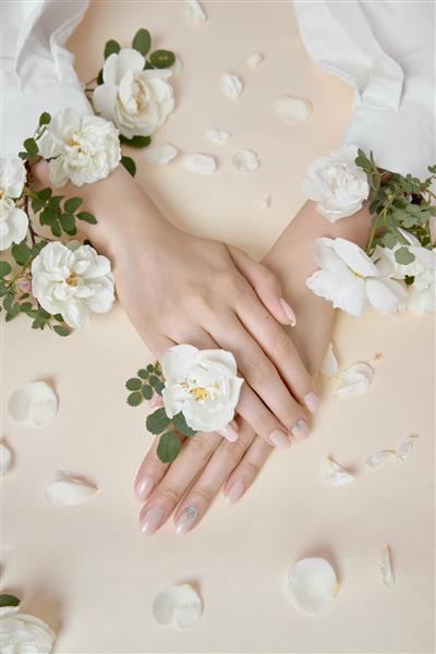 دستان زیبایی زن با گل های رز روی میز است لوازم آرایشی طبیعی برای مراقبت از پوست دست آرایش مد